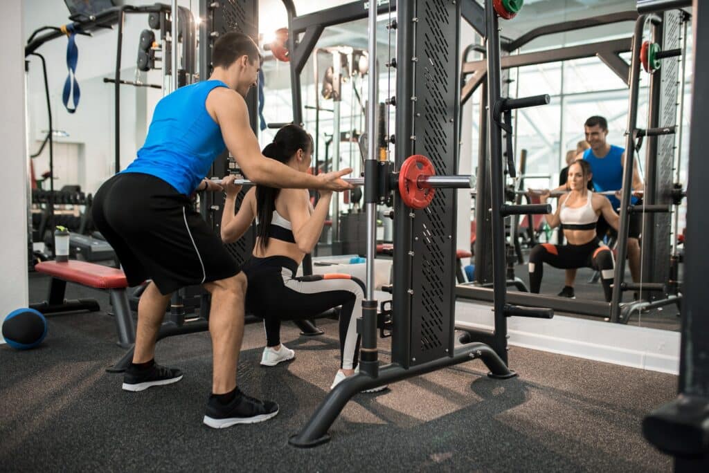 Gym Instructor Helping Young Woman