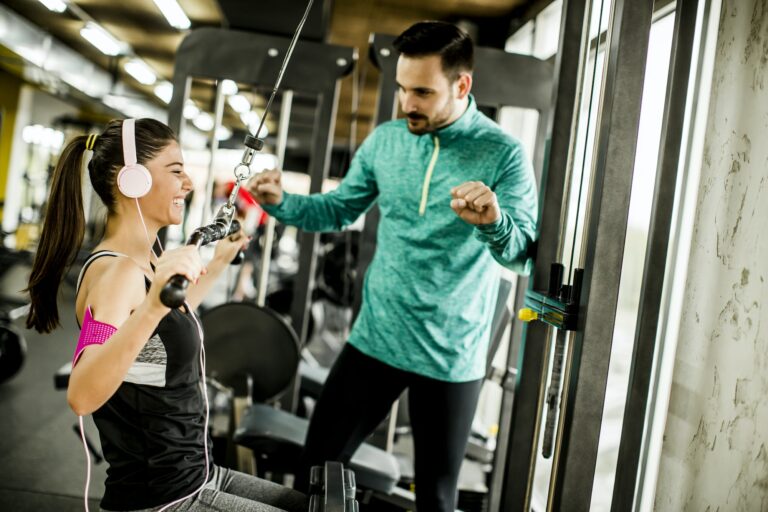 Young woman exercise with the help of trainer at the gym